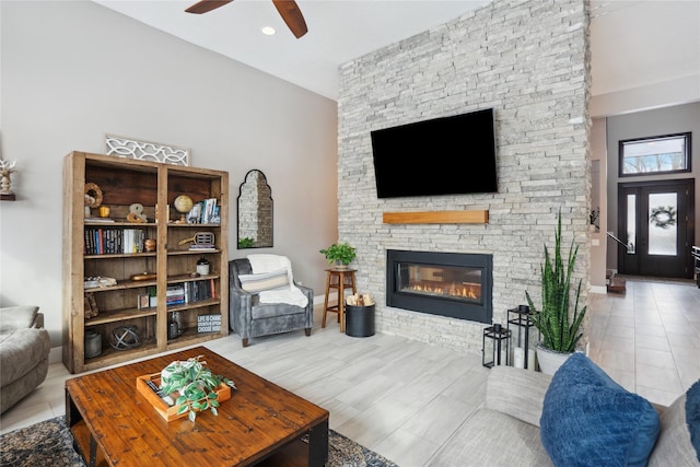 living room with a fireplace, light tile patterned flooring, and ceiling fan