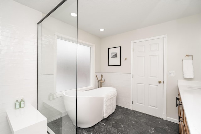 bathroom featuring a washtub, tile walls, and vanity