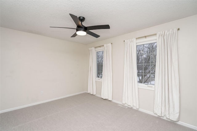 carpeted spare room featuring a textured ceiling and ceiling fan