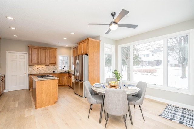 kitchen featuring appliances with stainless steel finishes, sink, light wood-type flooring, a kitchen island, and decorative backsplash