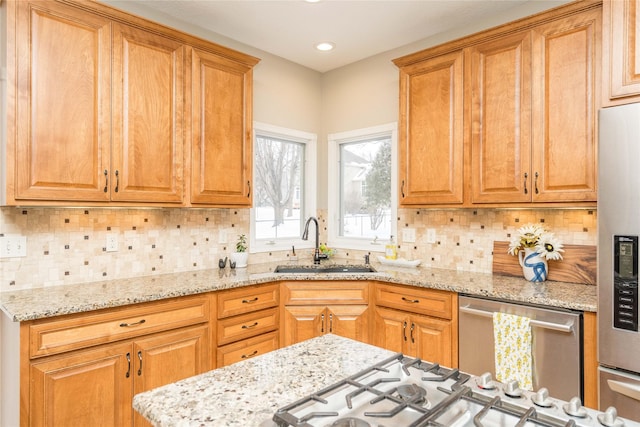 kitchen featuring appliances with stainless steel finishes, sink, tasteful backsplash, and light stone countertops