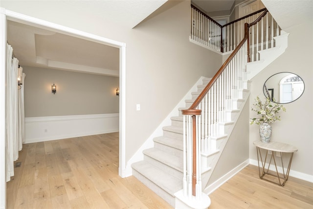 stairway featuring wood-type flooring and a towering ceiling