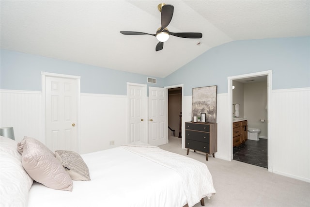 carpeted bedroom with ceiling fan, connected bathroom, and lofted ceiling