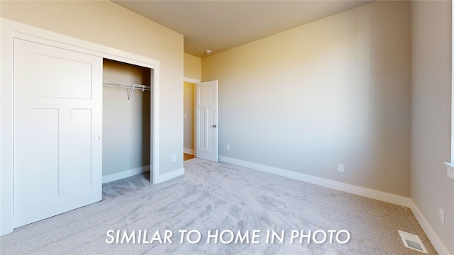 unfurnished bedroom with light carpet and a closet