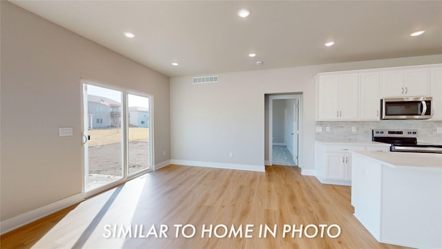 kitchen with decorative backsplash, light hardwood / wood-style floors, stainless steel appliances, and white cabinets