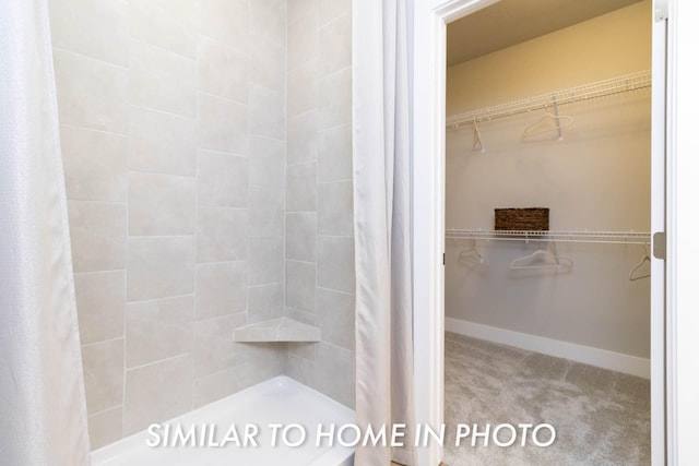 full bathroom featuring a shower stall, a spacious closet, and baseboards
