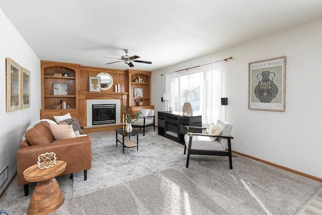 living room featuring ceiling fan, built in features, and a textured ceiling