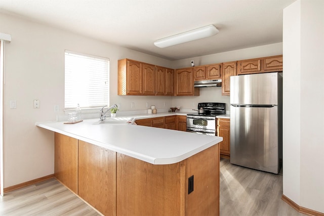 kitchen featuring light hardwood / wood-style floors, appliances with stainless steel finishes, sink, and kitchen peninsula