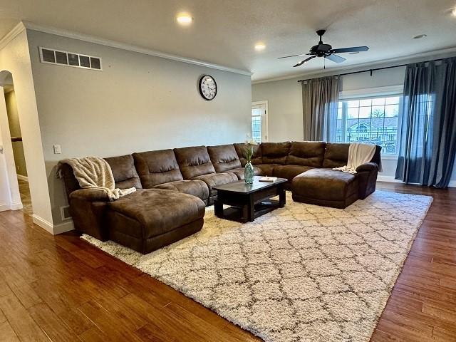 living room with crown molding, ceiling fan, and wood-type flooring