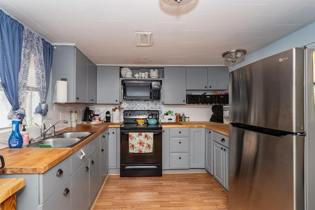 2003 Carroll St, Boone, IA 50036 - kitchen with wooden counters, gray cabinets, a sink, light wood-style flooring, and black appliances