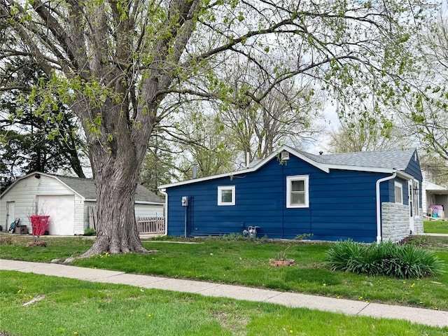 2003 Carroll St, Boone, IA 50036 - view of side of home with a shingled roof, stone siding, a garage, an outdoor structure, and a yard