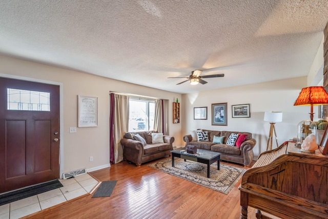 living room featuring light hardwood / wood-style floors, ceiling fan, and a textured ceiling