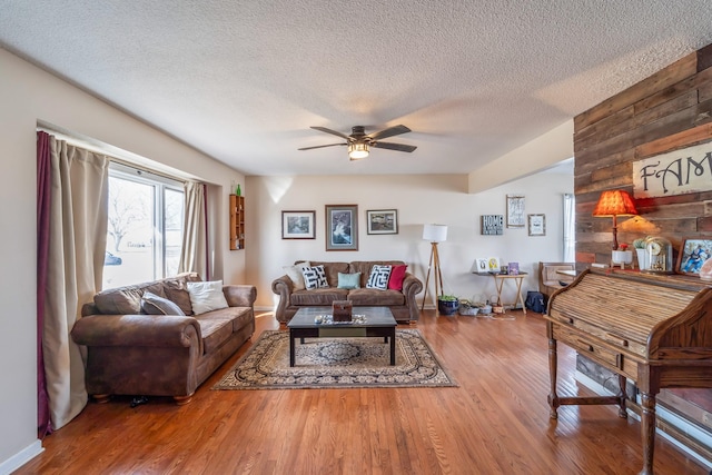 living room with ceiling fan, a textured ceiling, and hardwood / wood-style floors