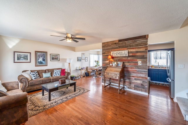 living room with ceiling fan, a textured ceiling, and hardwood / wood-style floors