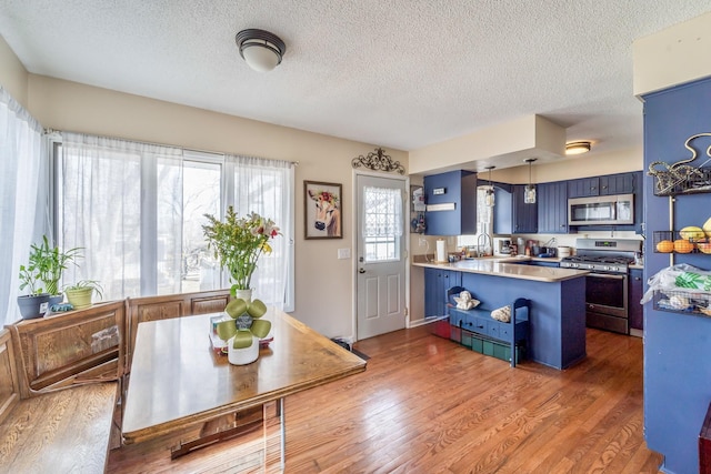 kitchen featuring a kitchen bar, blue cabinets, dark hardwood / wood-style floors, stainless steel appliances, and kitchen peninsula