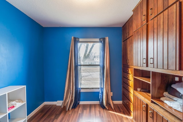 empty room featuring a textured ceiling and dark wood-type flooring