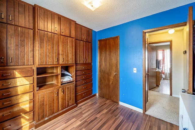 unfurnished bedroom with a textured ceiling, a closet, and dark hardwood / wood-style floors