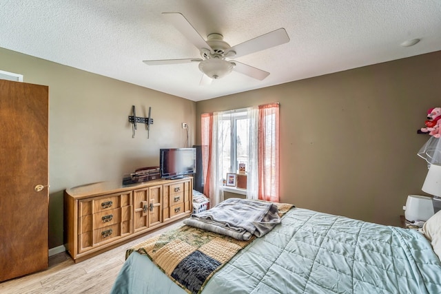 bedroom featuring light hardwood / wood-style floors, ceiling fan, and a textured ceiling