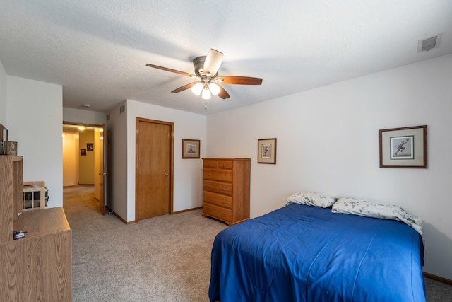 bedroom featuring a textured ceiling, light carpet, and ceiling fan