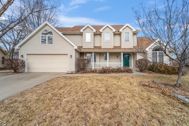 view of property featuring covered porch, a garage, and a front lawn