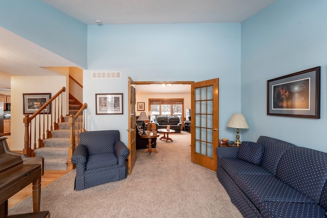 carpeted living room with a high ceiling and french doors