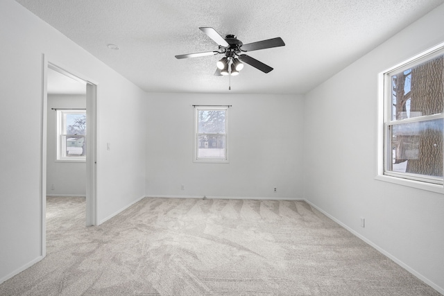 spare room with a textured ceiling, light carpet, and ceiling fan