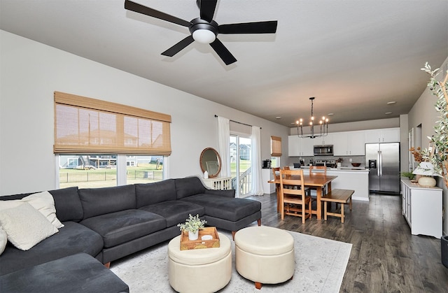 living room with ceiling fan with notable chandelier and dark hardwood / wood-style floors