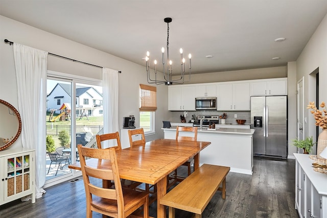 dining room with a notable chandelier, sink, and dark hardwood / wood-style floors