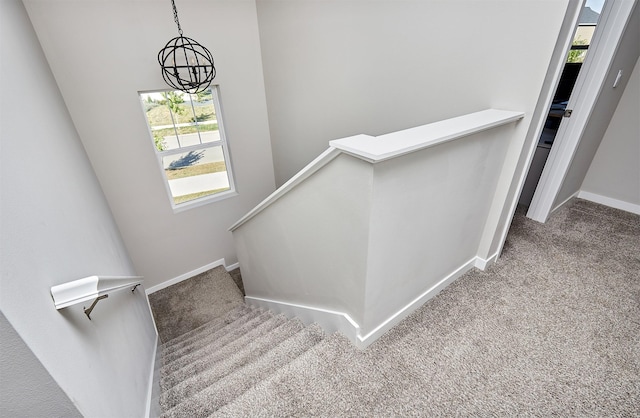 staircase featuring carpet and an inviting chandelier