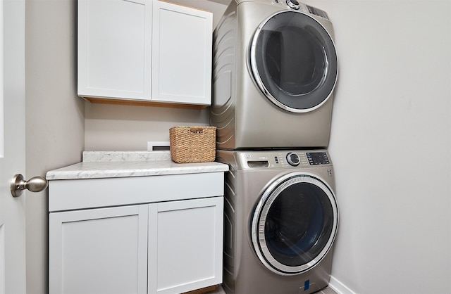 washroom featuring stacked washer / dryer and cabinets