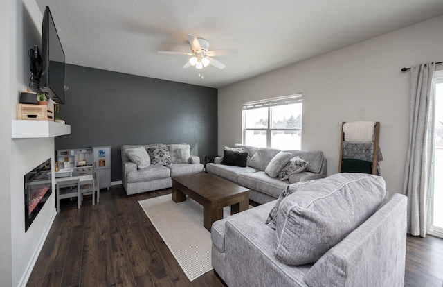 living room with a fireplace, dark wood-style flooring, baseboards, and ceiling fan