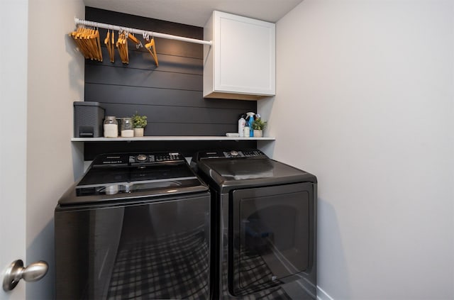 clothes washing area with cabinet space, baseboards, and independent washer and dryer