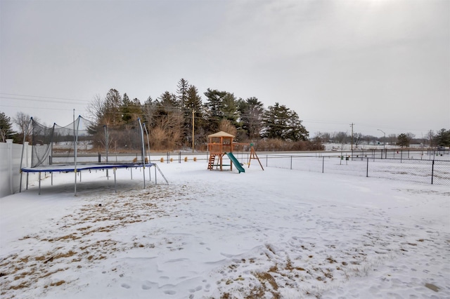 snow covered playground featuring playground community, a trampoline, and fence