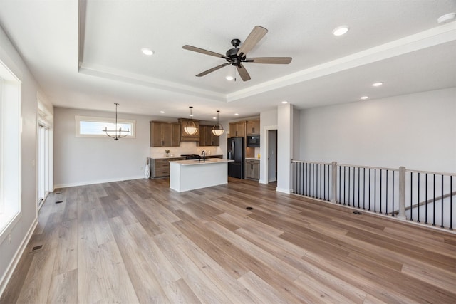 18274 Hidden Knl, Clive, IA 50325 - unfurnished living room featuring a raised ceiling, a sink, ceiling fan, light wood-style flooring, and recessed lighting