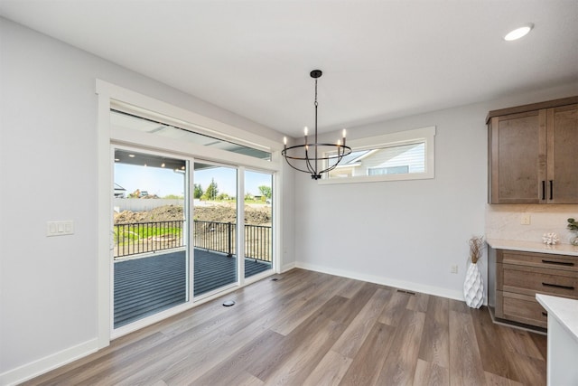 18274 Hidden Knl, Clive, IA 50325 - unfurnished dining area with a chandelier, wood finished floors, baseboards, and recessed lighting