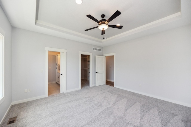 18274 Hidden Knl, Clive, IA 50325 - unfurnished bedroom featuring a tray ceiling, carpet floors, a walk in closet, baseboards, and a closet