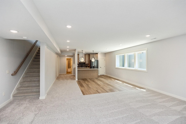 18274 Hidden Knl, Clive, IA 50325 - unfurnished living room with light carpet, stairs, baseboards, and recessed lighting