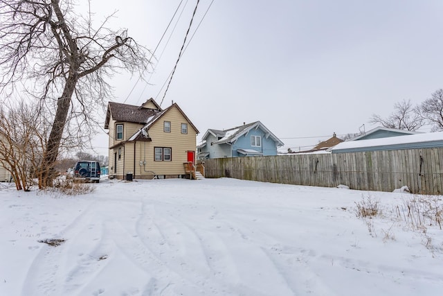 snow covered rear of property featuring fence