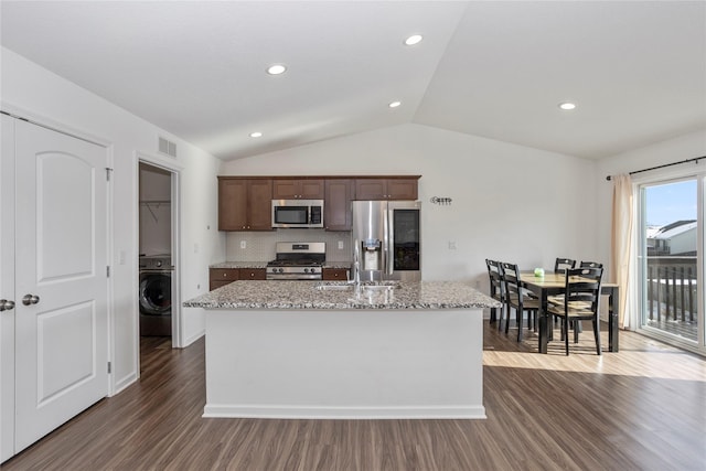 kitchen featuring stainless steel appliances, a sink, dark wood-style floors, washer / clothes dryer, and a center island with sink