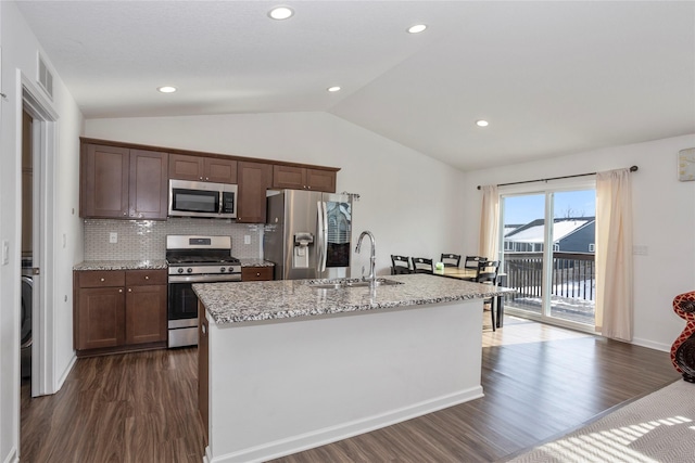 kitchen featuring vaulted ceiling, appliances with stainless steel finishes, a sink, and a center island with sink