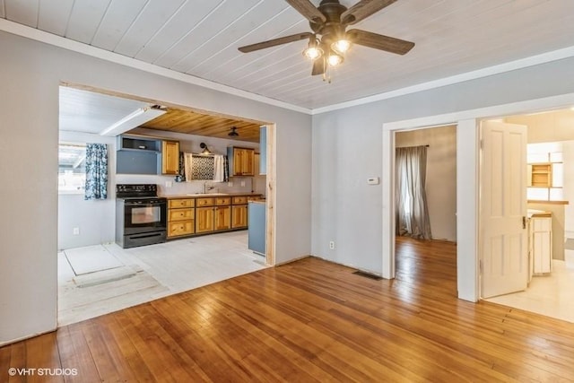 kitchen with brown cabinetry, light wood-style flooring, crown molding, black range with electric cooktop, and a sink