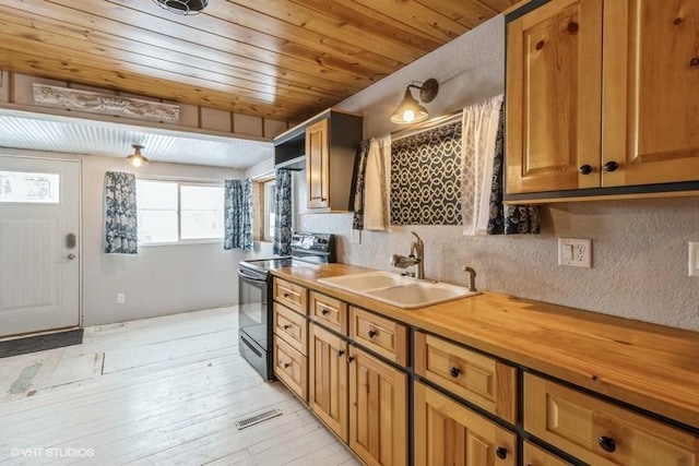 kitchen featuring wood ceiling, backsplash, brown cabinets, black range with electric stovetop, and a sink