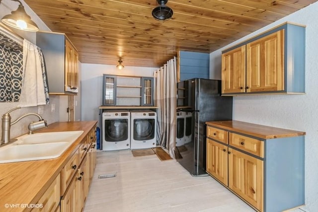 kitchen featuring a sink, butcher block countertops, washer and dryer, and freestanding refrigerator