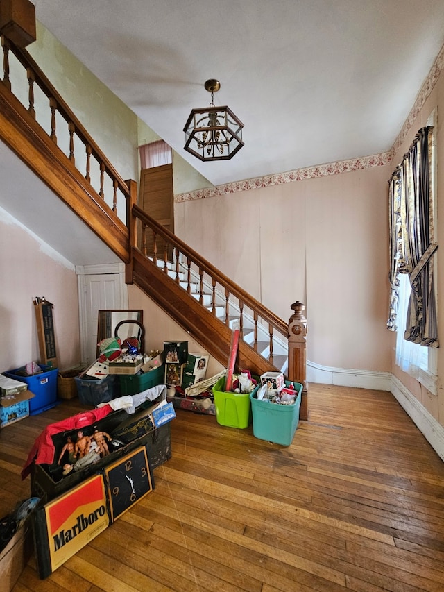 rec room featuring baseboards, an inviting chandelier, and wood finished floors