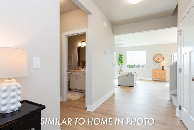 corridor featuring light wood-style flooring, stairs, and baseboards