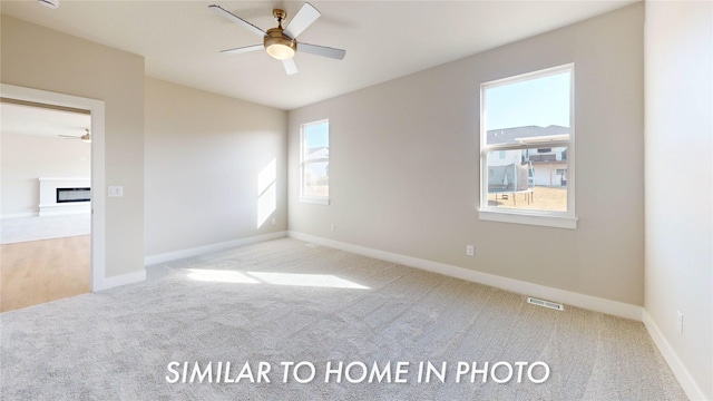 unfurnished room featuring light carpet, ceiling fan, a fireplace, and visible vents