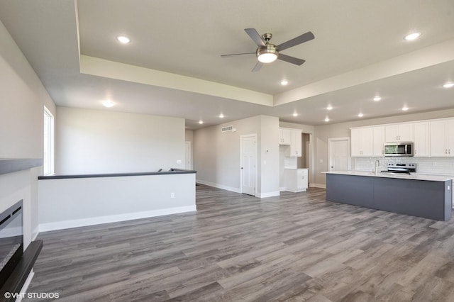 1020 2nd St NE, Altoona, IA 50009 - unfurnished living room with a tray ceiling, a ceiling fan, recessed lighting, and wood finished floors