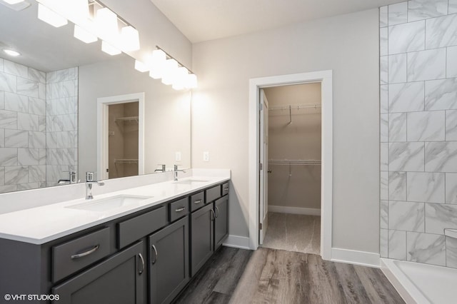 1020 2nd St NE, Altoona, IA 50009 - bathroom featuring wood finished floors, double vanity, a spacious closet, and a tile shower