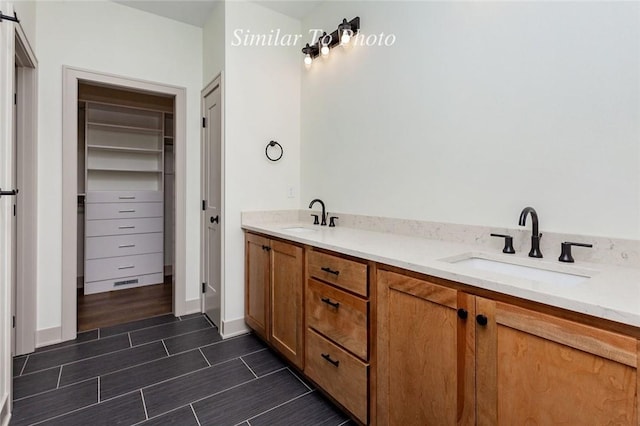 full bath featuring double vanity, wood tiled floor, a walk in closet, and a sink