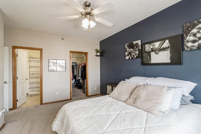 bedroom with connected bathroom, light colored carpet, baseboards, a closet, and a walk in closet